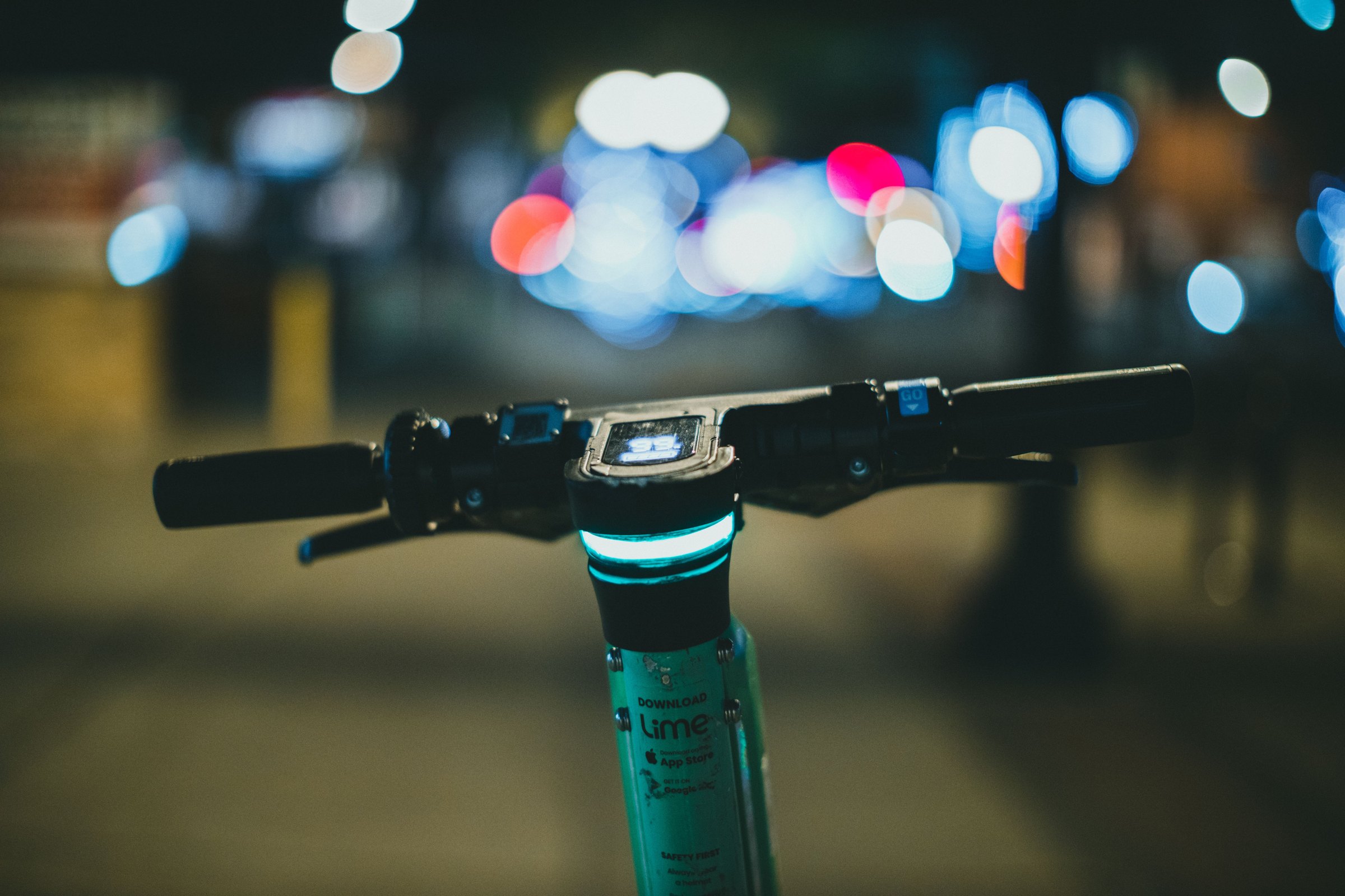 Guidon de trottinette électrique éclairé en gros plan de nuit, lumières urbaines en arrière-plan