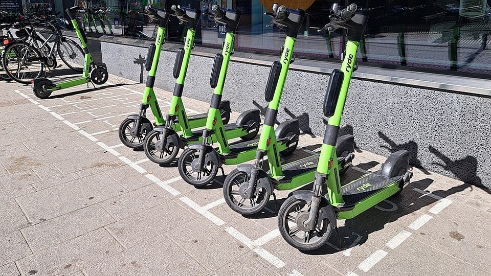 Trottinettes électriques vertes garées en ligne sur des emplacements marqués