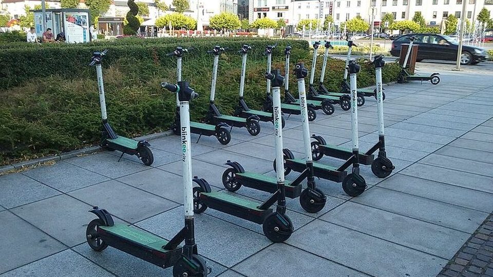 Trottinettes électriques alignées près d’un espace vert urbain